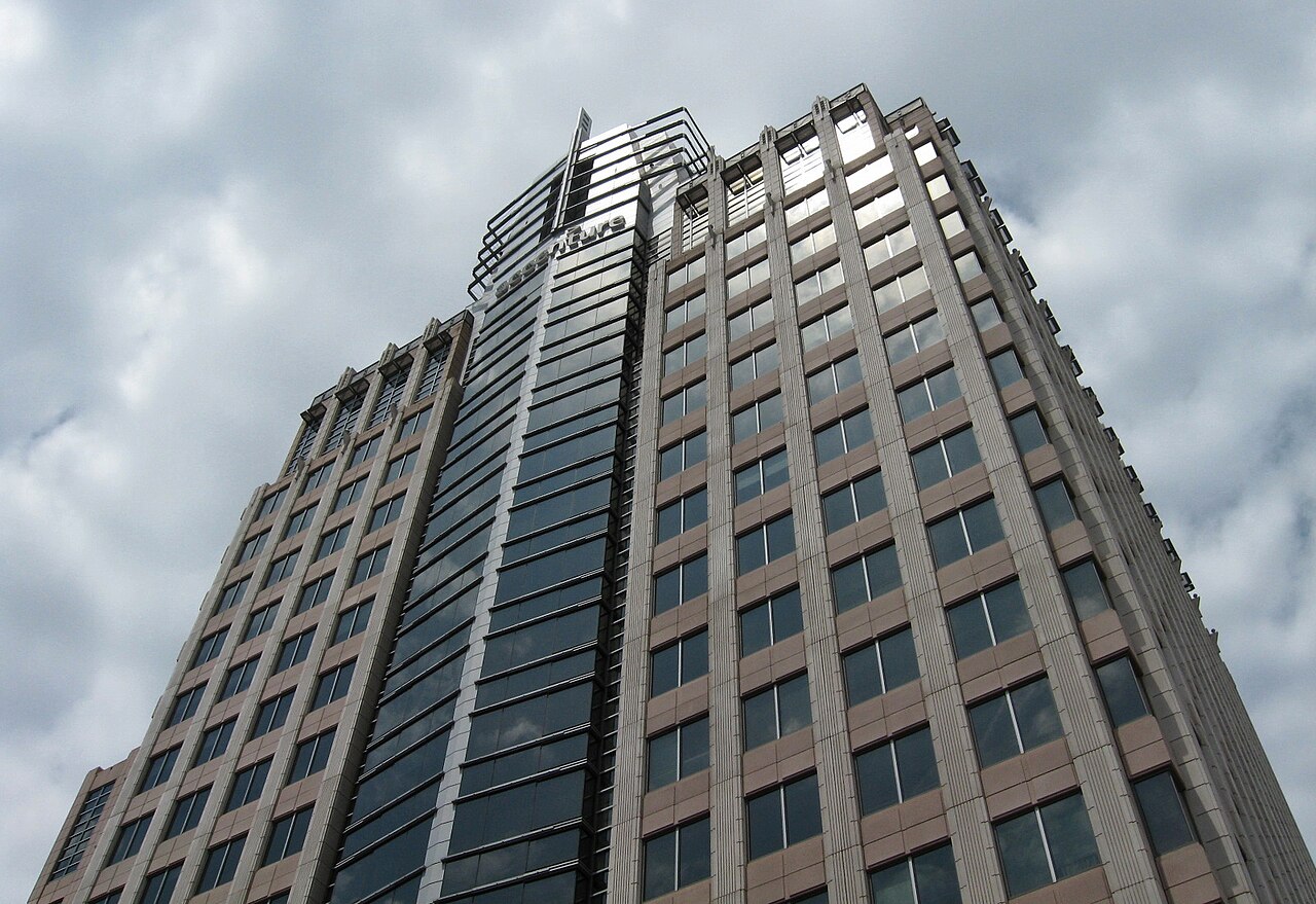 Looking up at a tall office tower with the Accenture name at the top against a cloudy sky