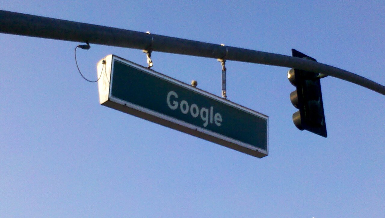 A street sign reading Google against a clear blue sky.
