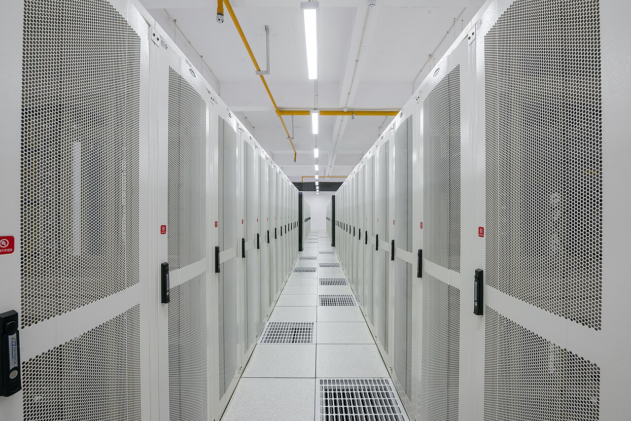Rows of server racks with perforated cabinet doors in a commercial data center aisle