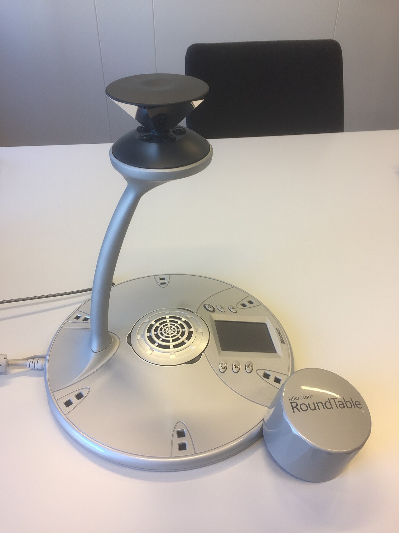 A Microsoft RoundTable 360-degree conference camera and speakerphone unit on a meeting room table