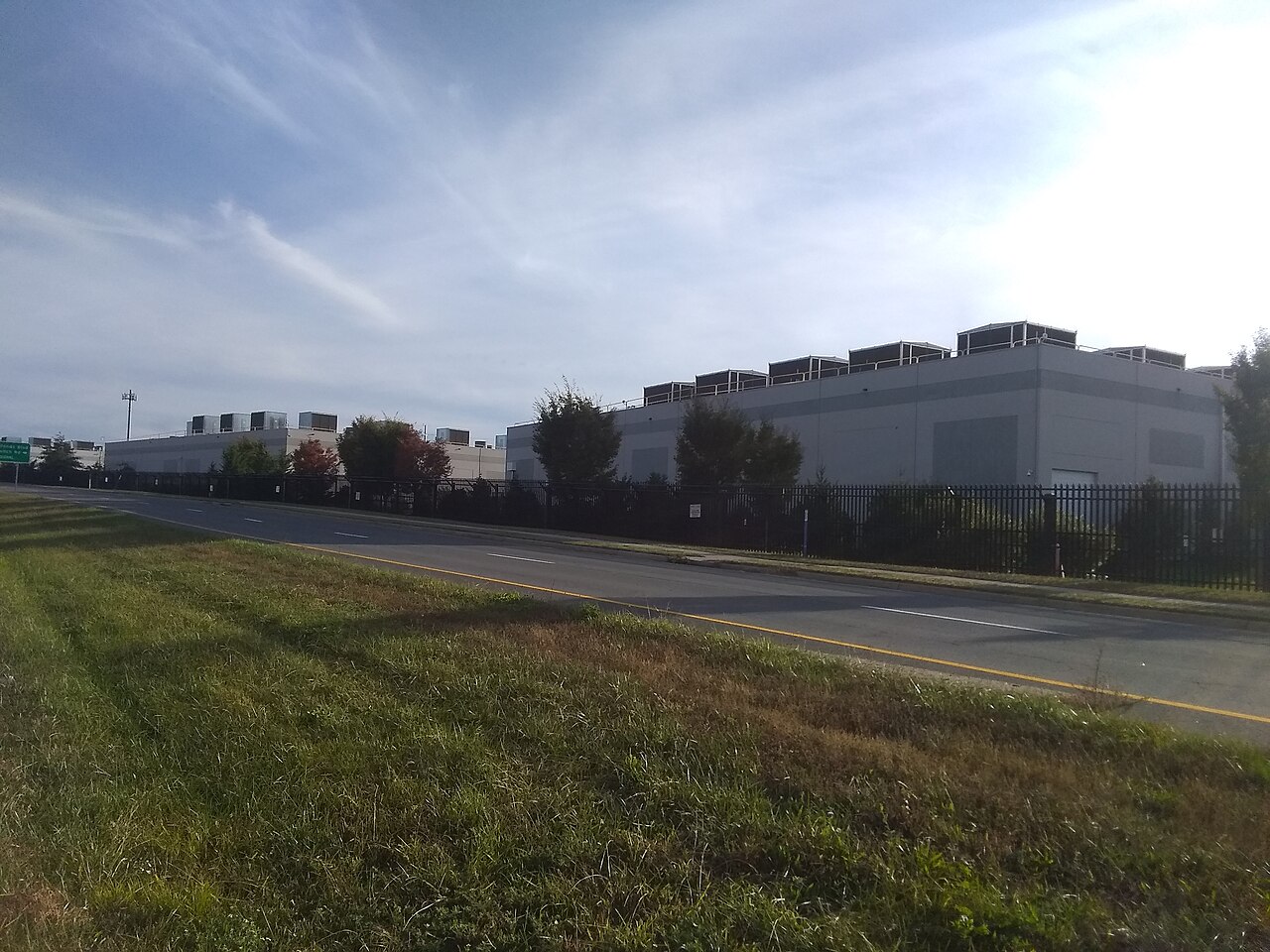 AWS data center buildings with rooftop cooling units behind a security fence in Ashburn, Virginia