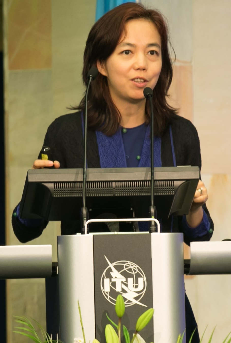 Fei-Fei Li speaking at a podium at the AI for Good summit in 2017