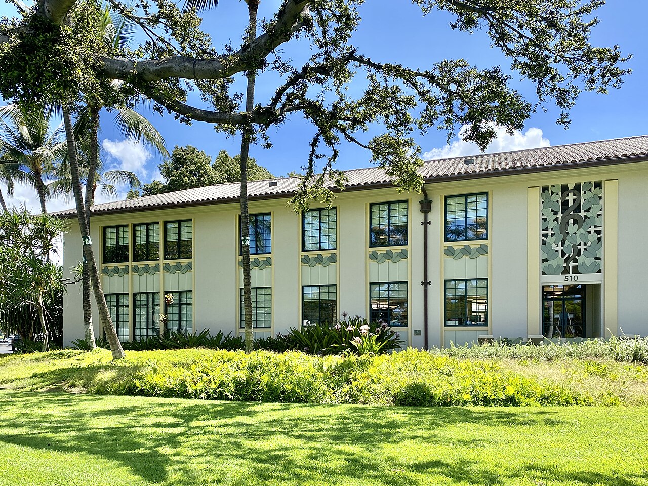 A medical center building fronted by lawn and trees under a blue sky
