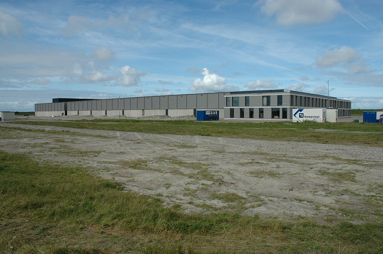 A large data center building set in an open field under a cloudy sky