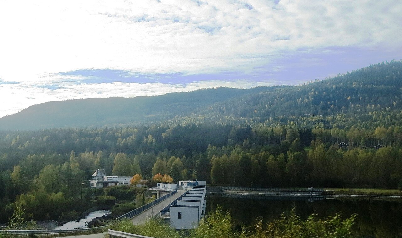A hydroelectric dam and power station set in a forested Norwegian river valley