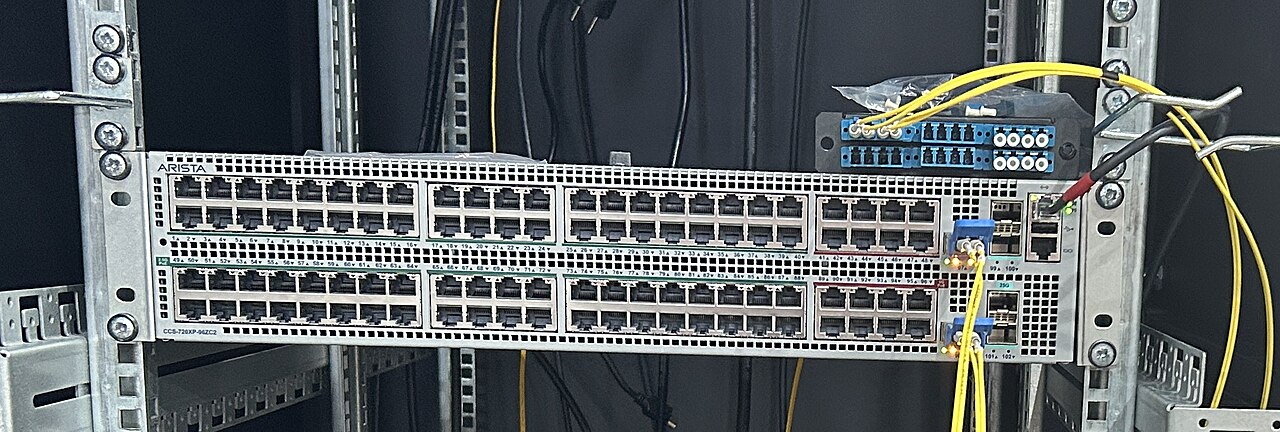 An Arista Networks data-center switch mounted in a server rack with fiber cabling