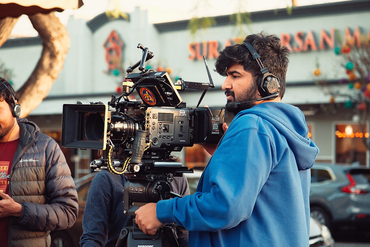A camera operator with a cinema camera on a film set at dusk