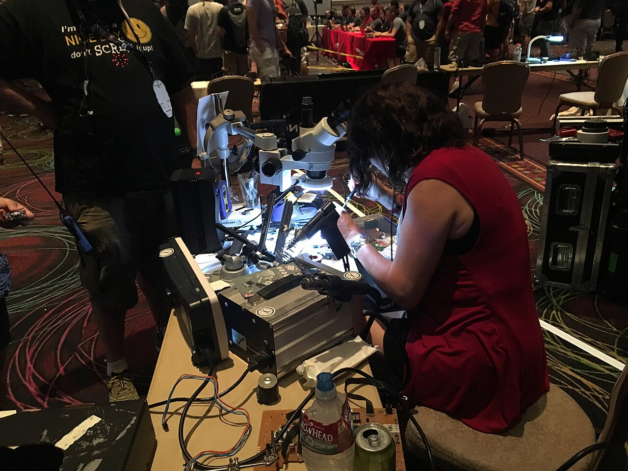 A security researcher examining hardware under a microscope at the DEF CON security conference