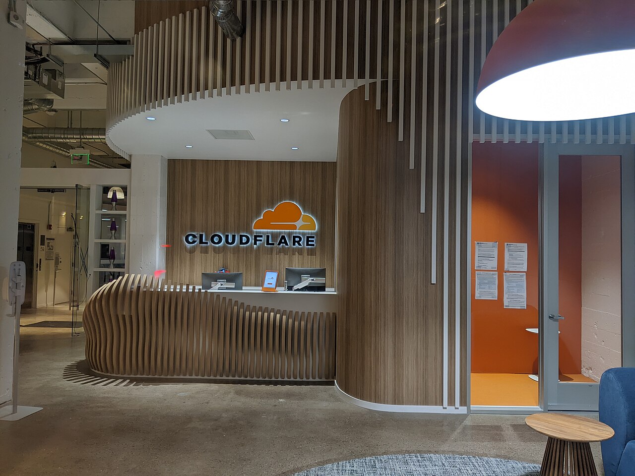 Reception area of a Cloudflare office with the Cloudflare logo behind a wooden desk
