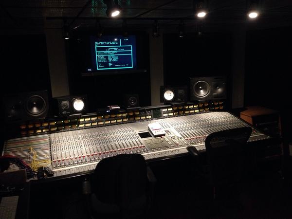 A large analog mixing console in a professional recording studio control room