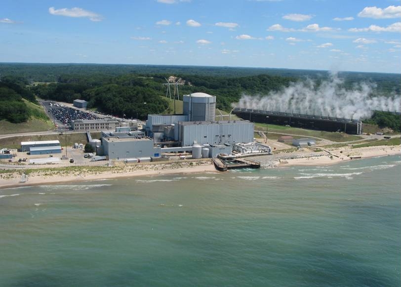Aerial view of the Palisades nuclear plant on the Lake Michigan shoreline with cooling vapor rising behind the reactor building