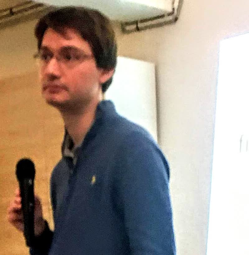 François Chollet holding a microphone while speaking at an event