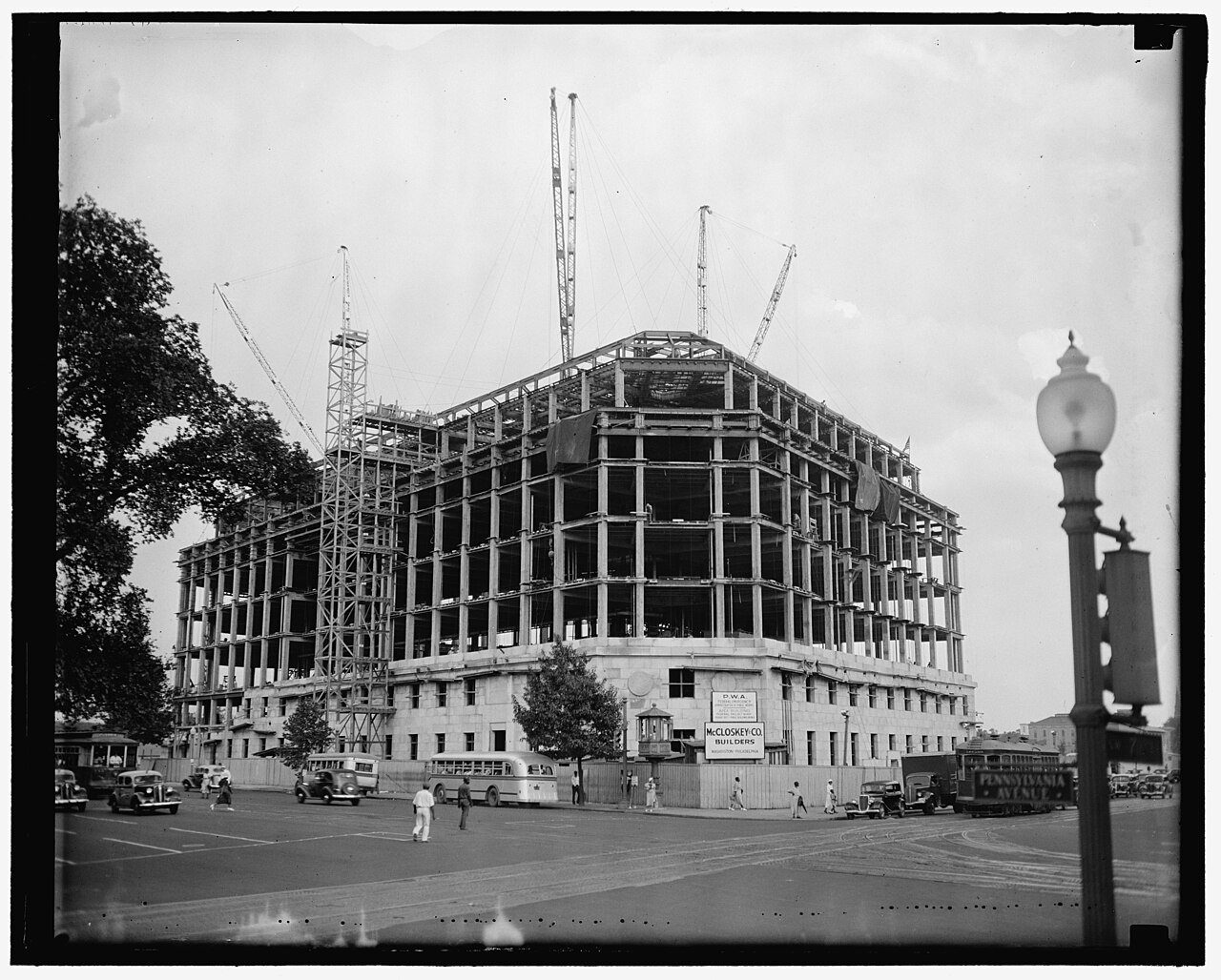 Black and white photograph of the Apex building in Washington, D.C., under construction with cranes overhead