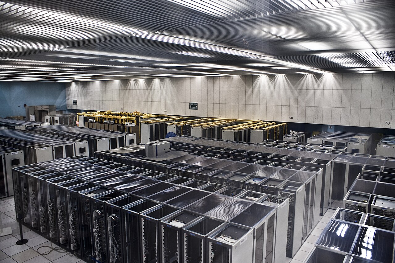 A large data center hall filled with rows of computing racks