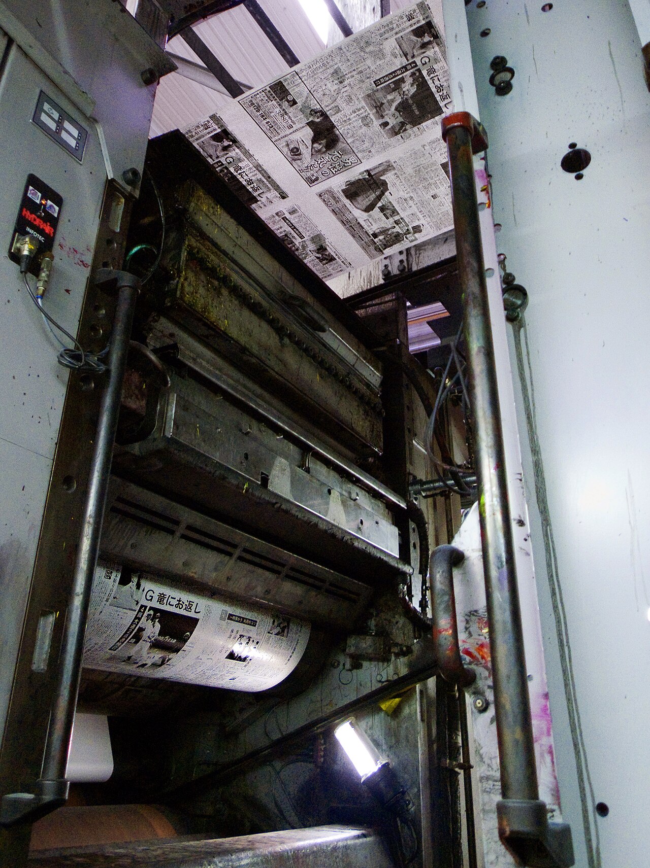 Newsprint running through a web-fed offset press, seen from below