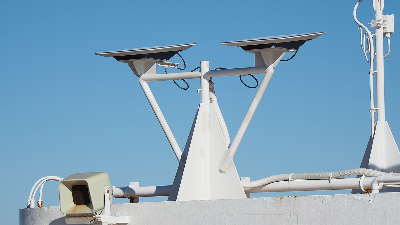 Two Starlink flat-panel antennas mounted on white brackets on a ship's superstructure against a blue sky