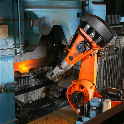 An orange industrial robot arm handling glowing hot metal inside an automated foundry cell