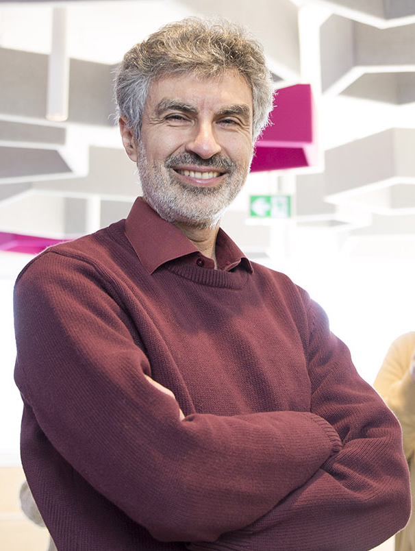 Portrait of Yoshua Bengio smiling with arms crossed, wearing a maroon sweater
