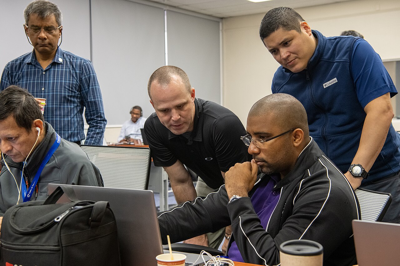 A group of cybersecurity practitioners working together at laptops during an incident response exercise