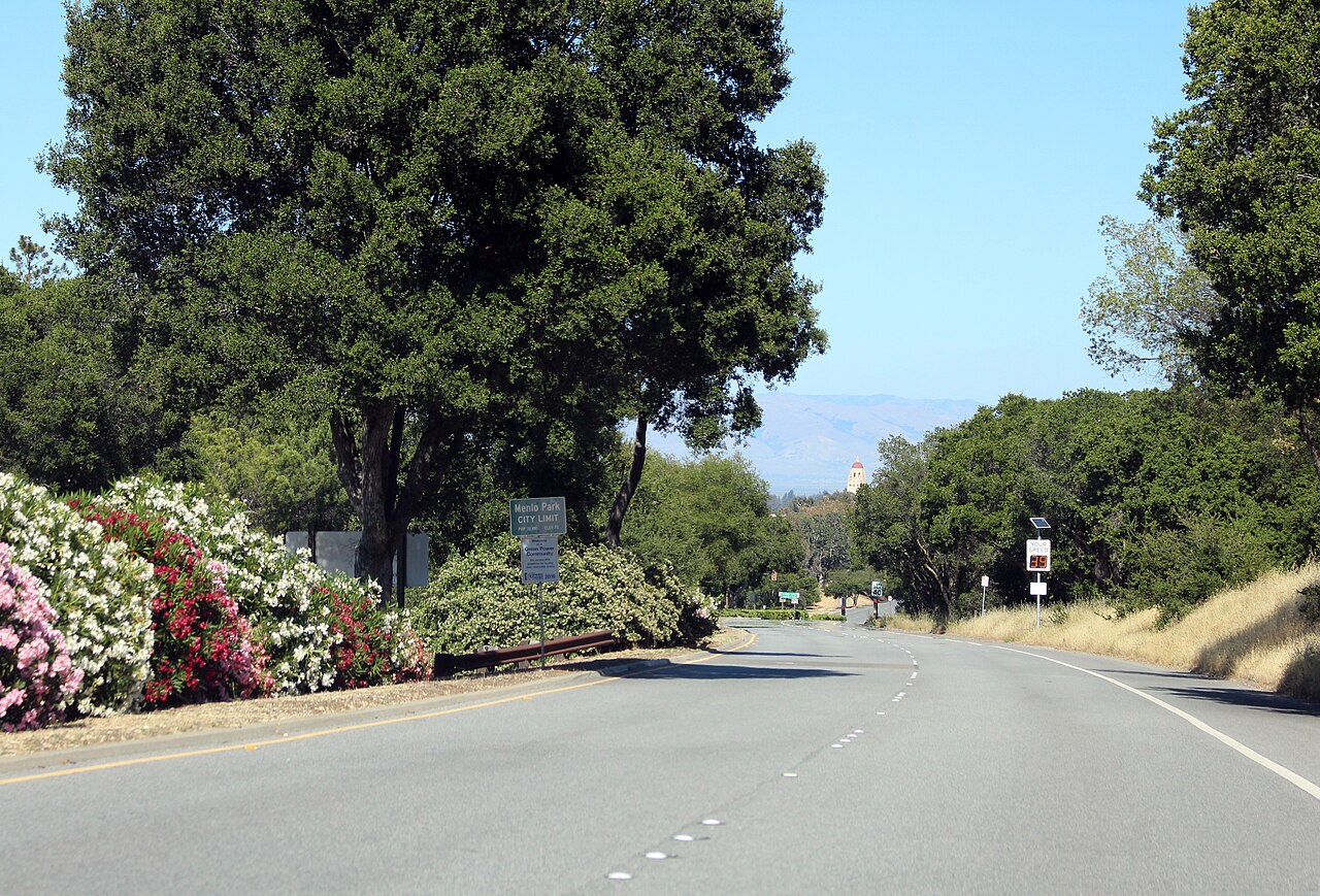 Sand Hill Road in Menlo Park, California, looking east with the Menlo Park city limit sign and Hoover Tower in the distance