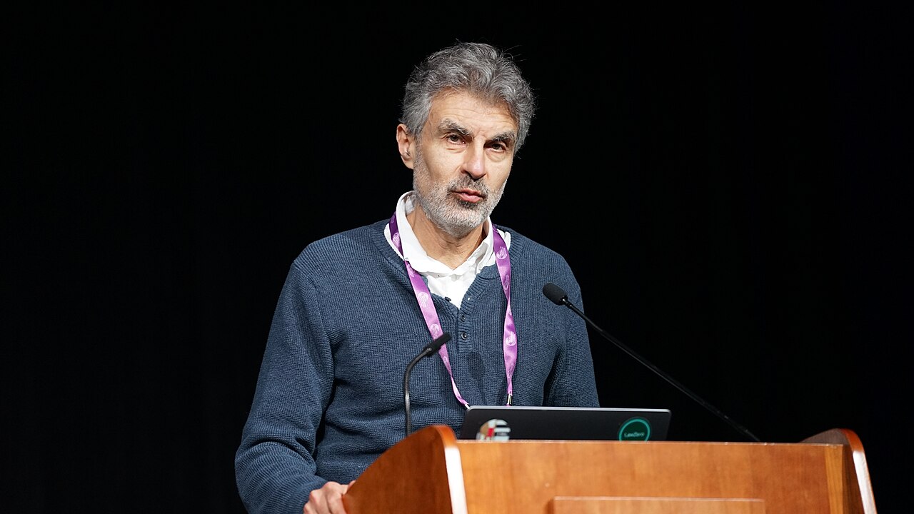 Yoshua Bengio speaking at a lectern at a conference in San Diego
