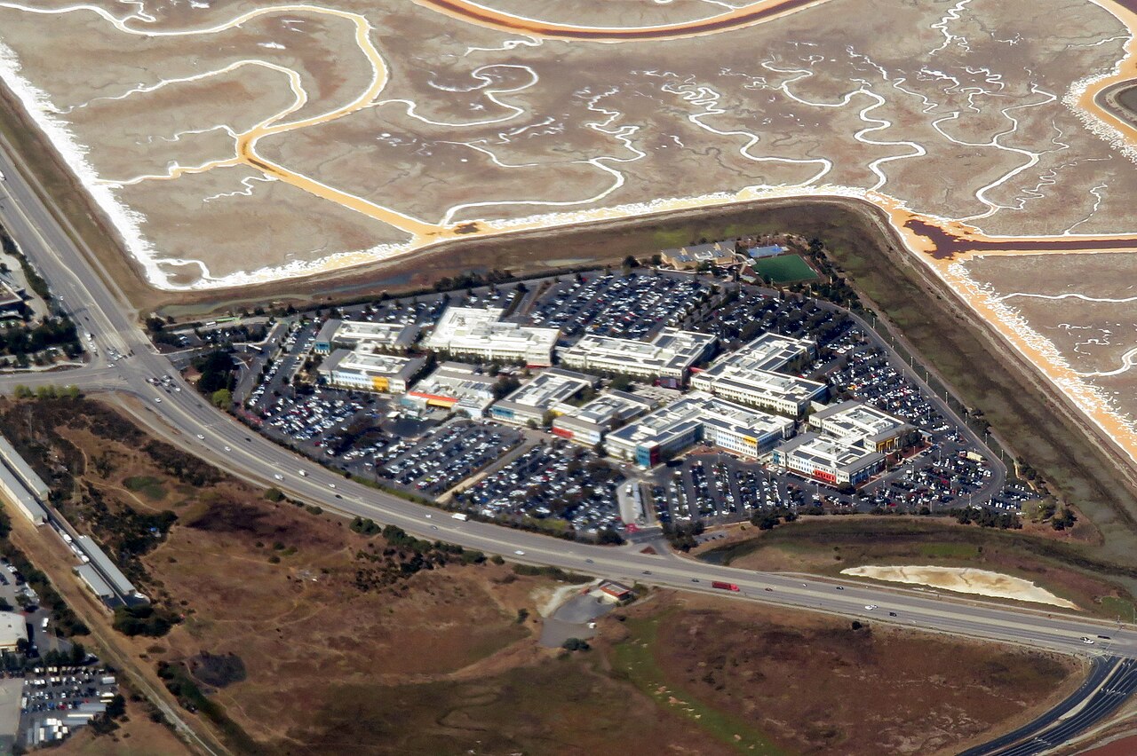 Aerial view of the Facebook campus in Menlo Park, California, with office buildings, parking lots and surrounding salt marsh