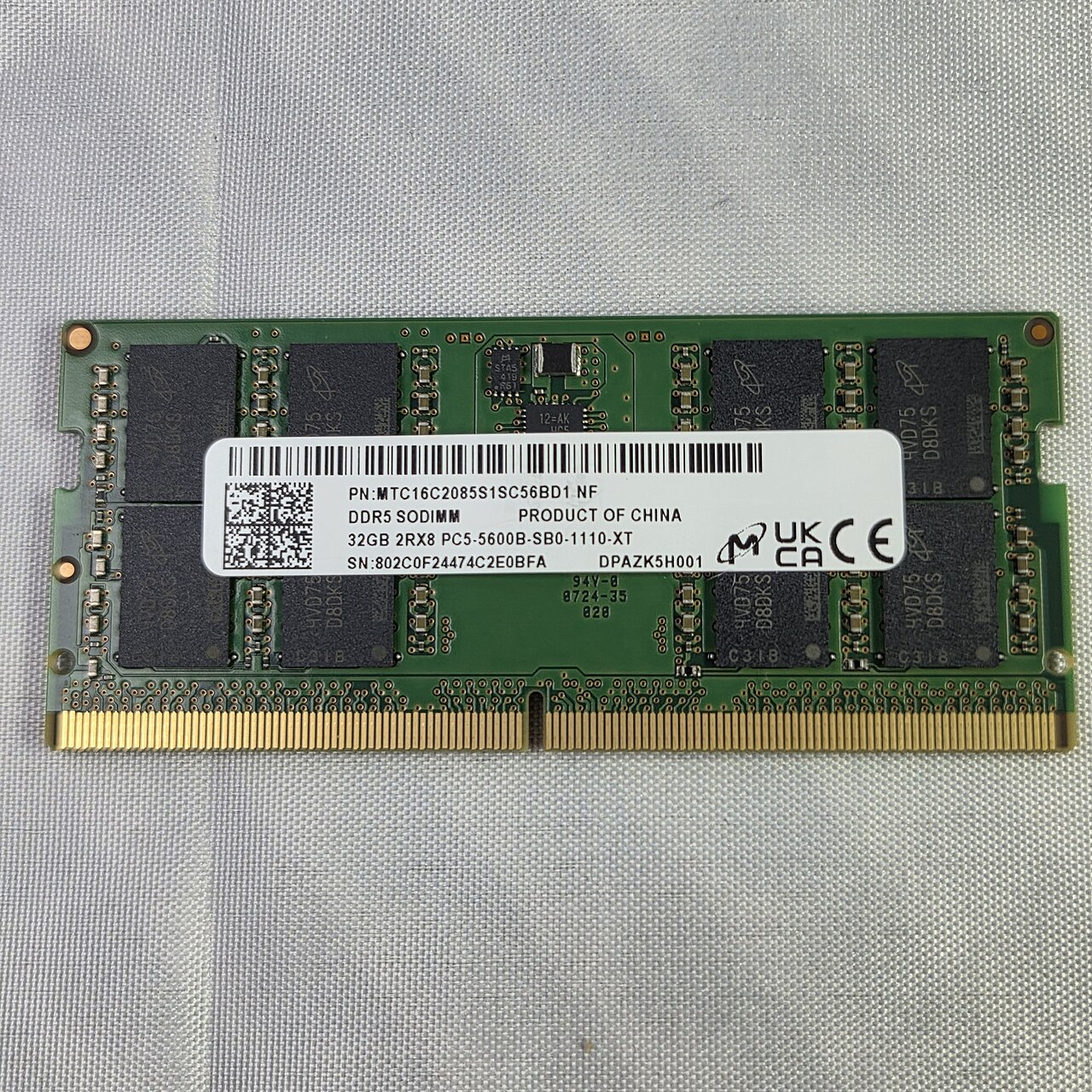 A Micron 32 GB DDR5 SO-DIMM memory module lying on a grey cloth