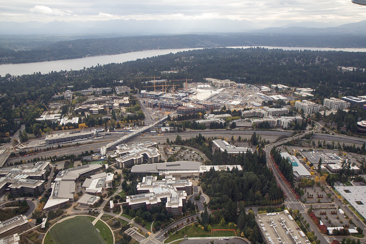 Aerial view of Microsoft's Redmond, Washington campus showing office buildings, roads and construction cranes amid green landscape
