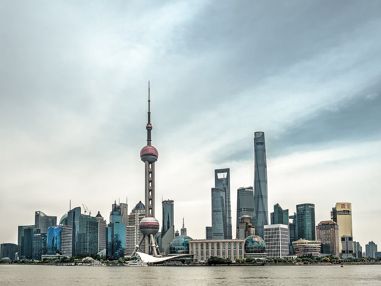 Daytime view of the Pudong skyline in Shanghai, China, including the Oriental Pearl Tower and Shanghai Tower, seen across the Huangpu River