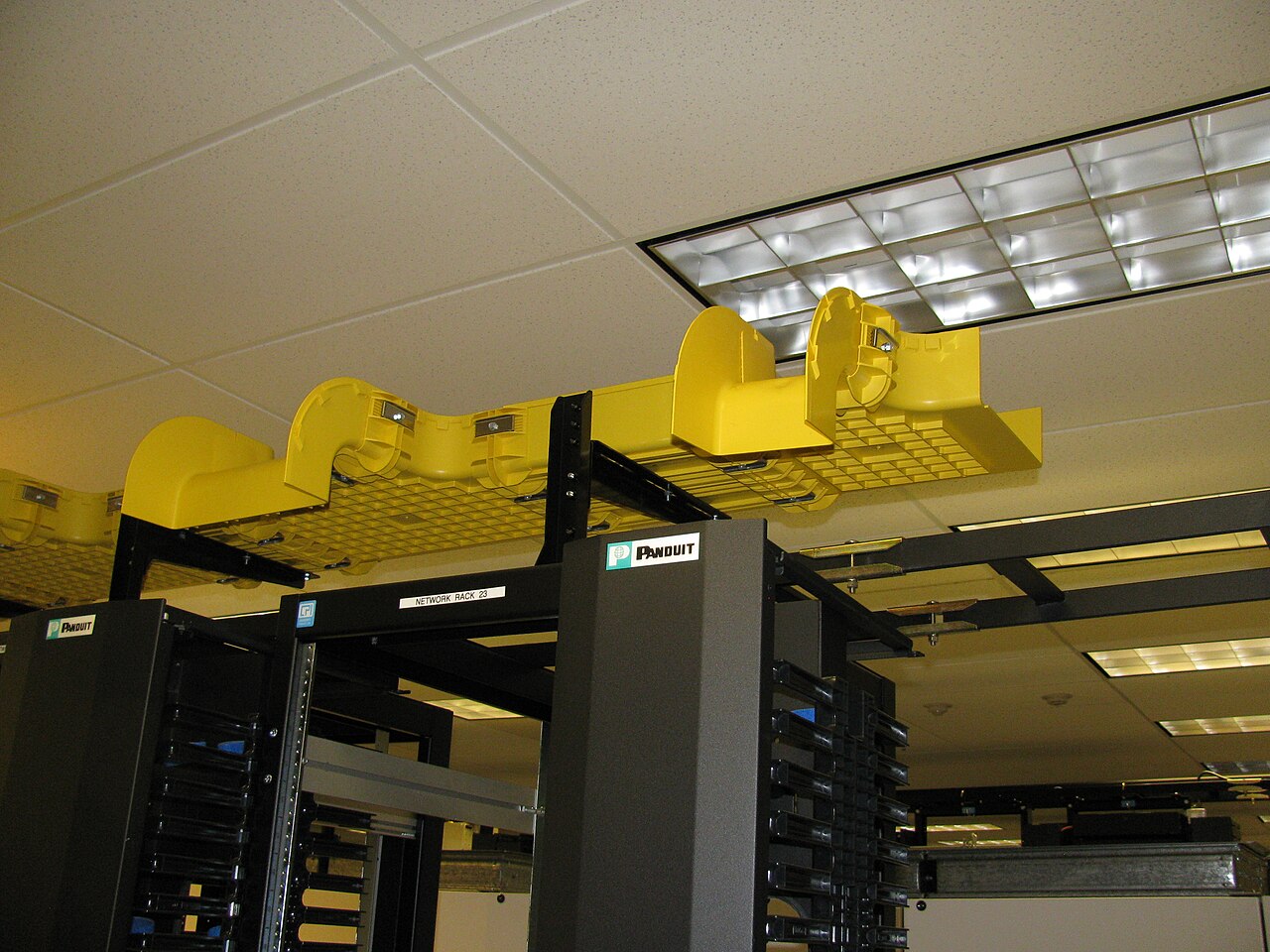Yellow fiber-optic cable management above data-center network racks