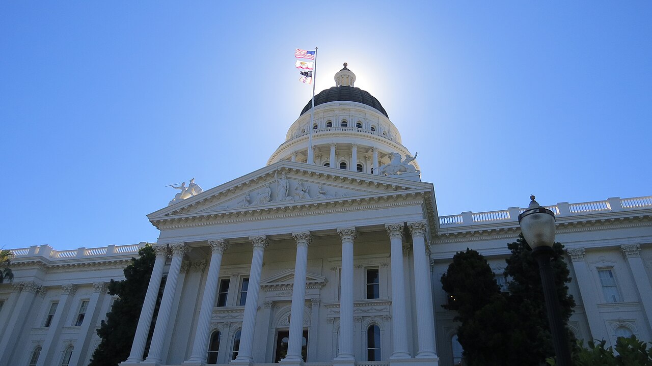 Low-angle view of the California State Capitol in Sacramento, its dome backlit by the morning sun