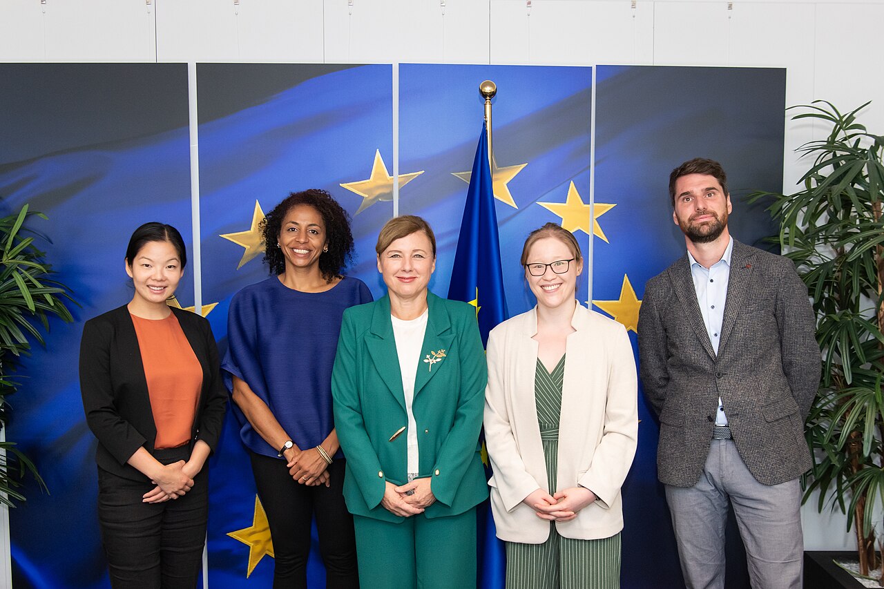 Five OpenAI representatives standing in front of a European Union flag during a visit to the European Commission