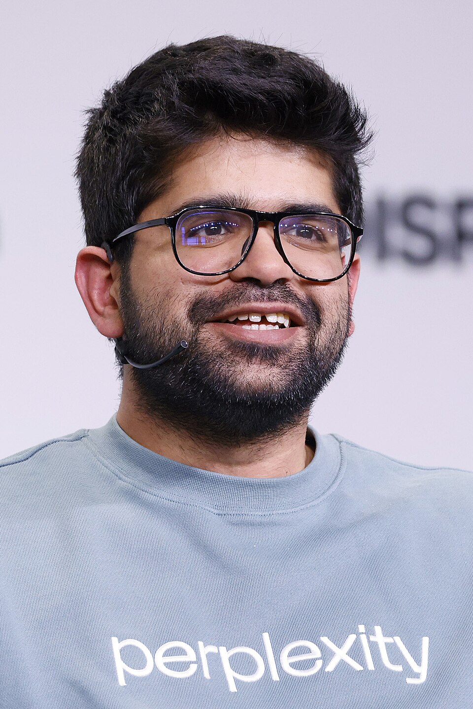 Aravind Srinivas, co-founder and CEO of Perplexity, speaking onstage in a Perplexity branded shirt