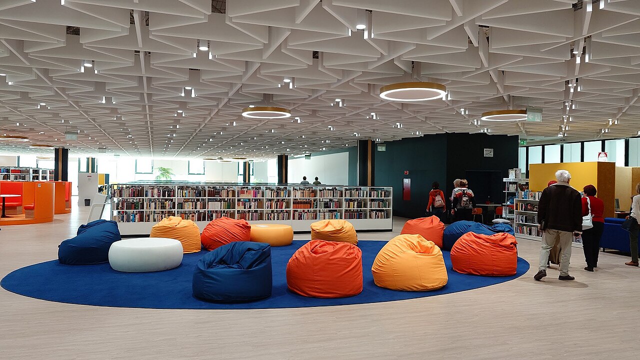 A modern university library reading room with bookshelves and colorful seating