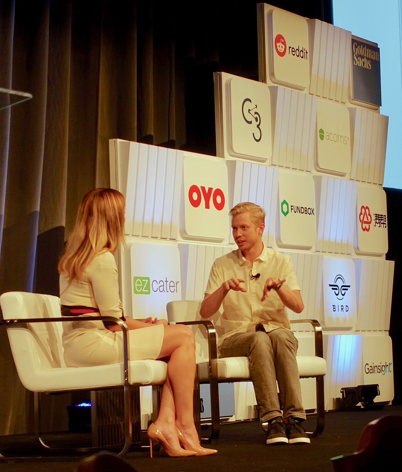 Reddit CEO Steve Huffman speaking on stage at a Goldman Sachs conference with the Reddit logo on the backdrop