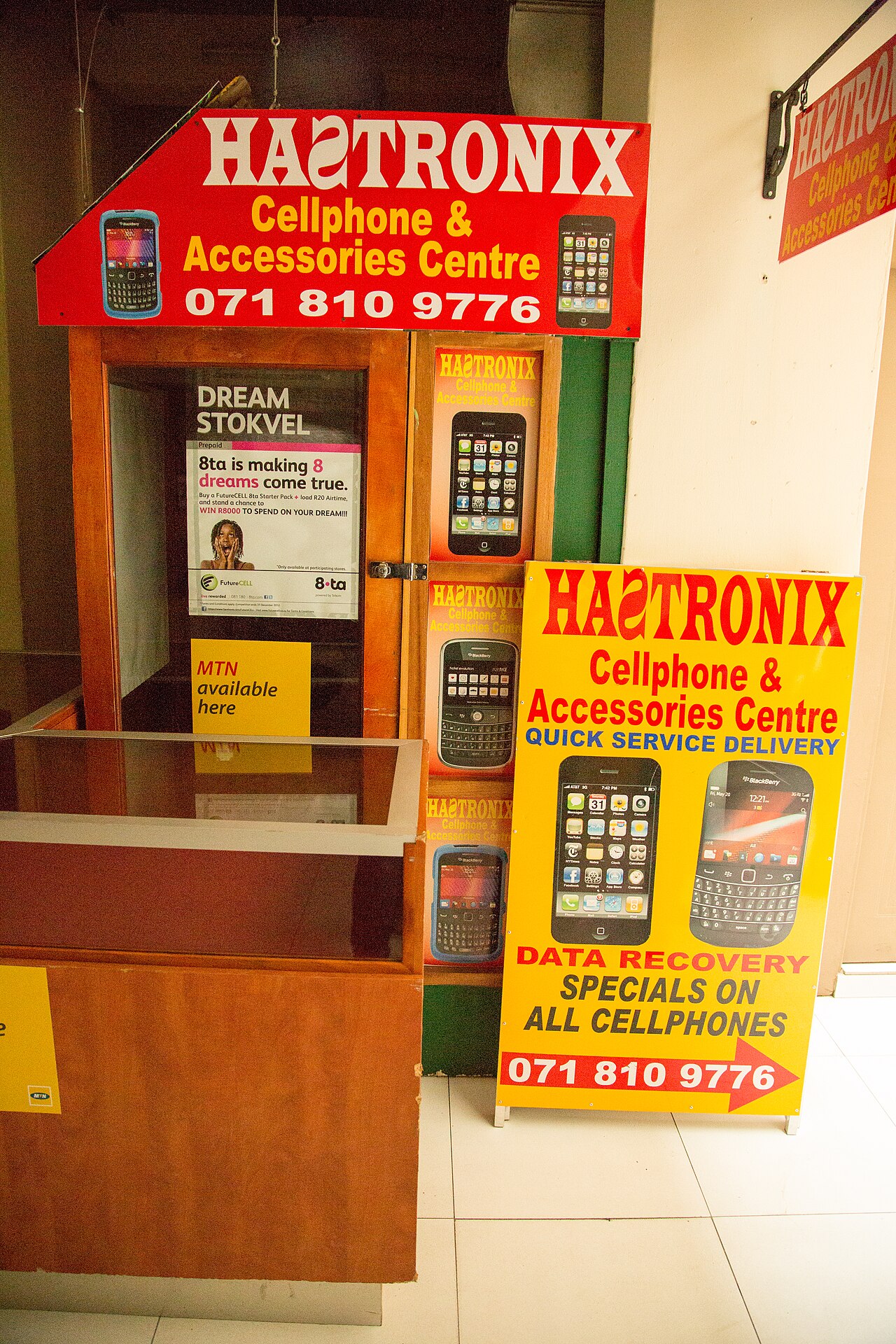 A small cellphone and accessories kiosk with painted signs and phone posters in Cape Town, South Africa