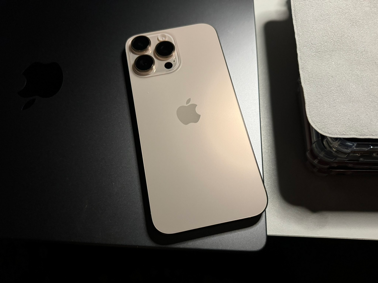 An iPhone 16 Pro Max in Desert Titanium resting on a MacBook