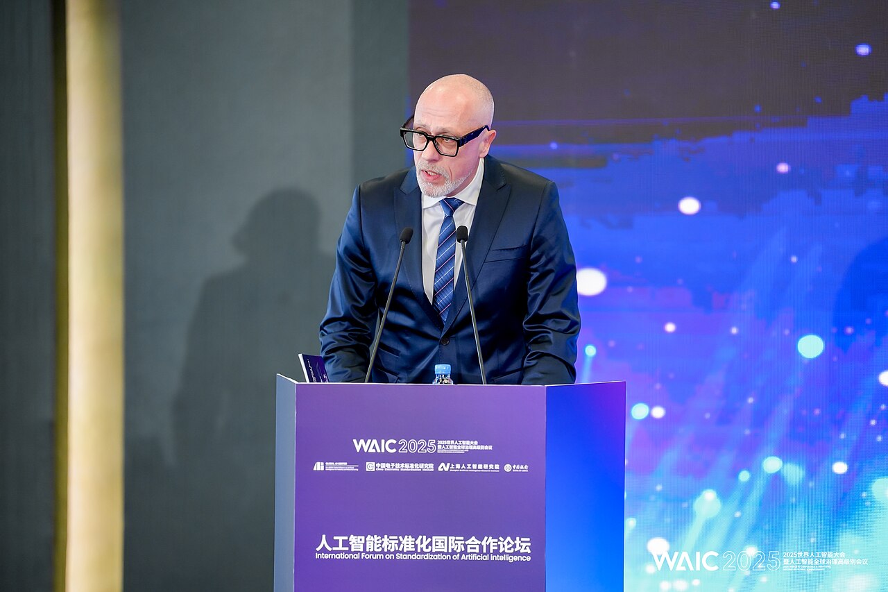 A speaker at a podium branded WAIC 2025, International Forum on Standardization of Artificial Intelligence, in Shanghai