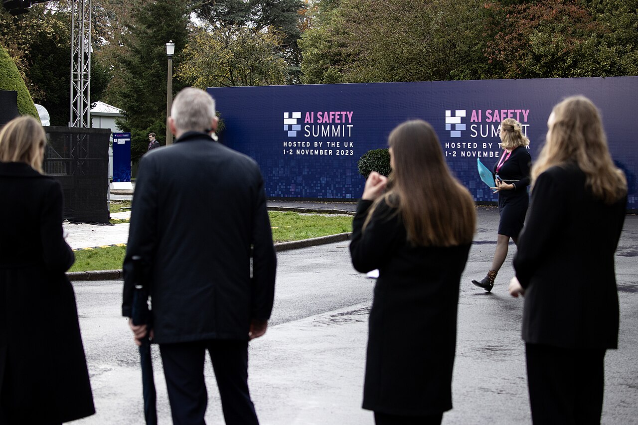 Delegates walking toward AI Safety Summit signage at Bletchley Park on 1 November 2023